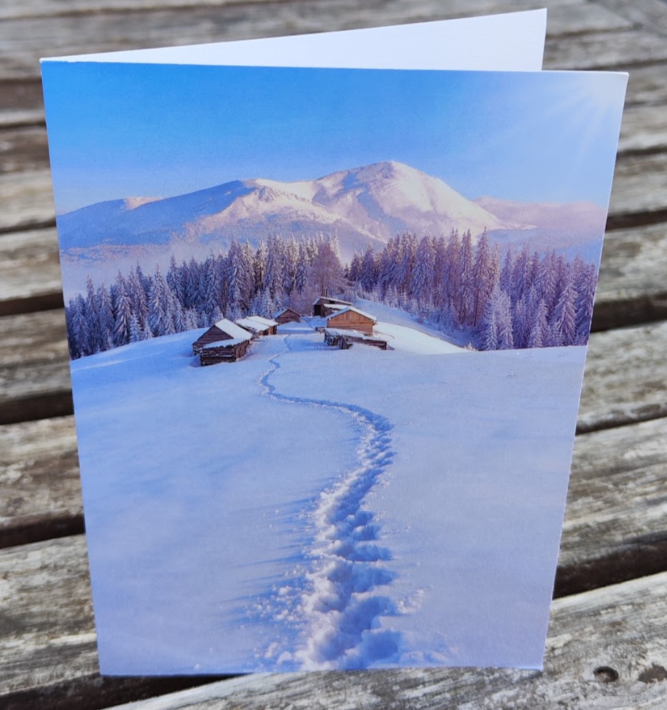 Winterliche Grußkarte mit Spuren im Schnee zur Bergalm, in verschneiter Gebirgslandschaft.