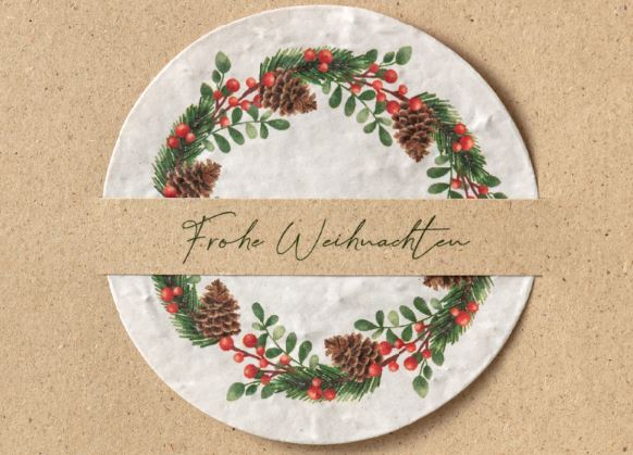 Naturbraune Weihnachtskarte aus Graspapier und eingesteckte Kugel aus Samenpapier mit floralem Kranz