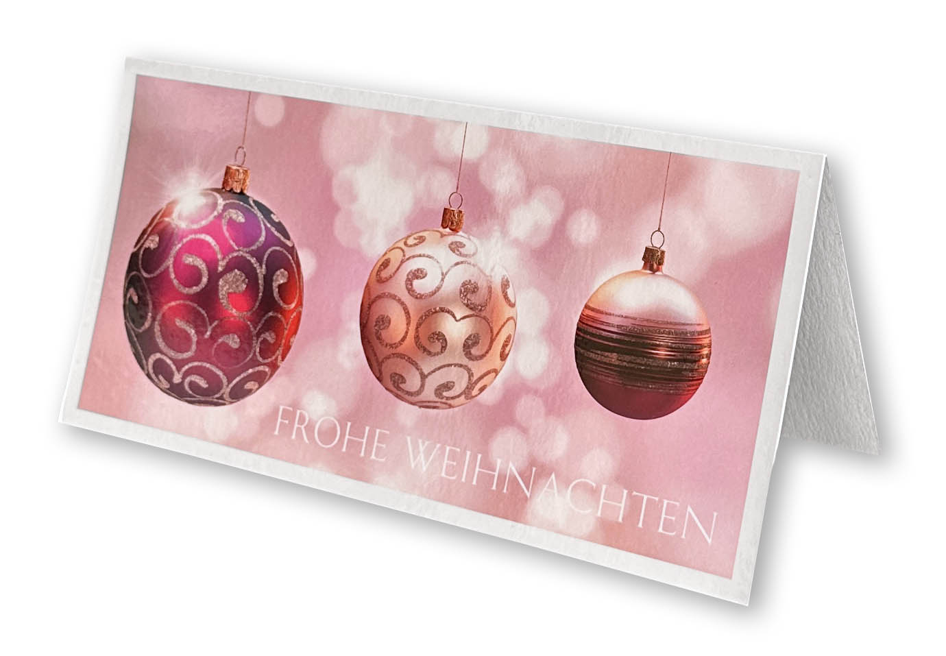 Weihnachtskarte mit hängenden Christbaumkugeln auf rosafarbenem Hintergrund und Gruß "Frohe Weihnachten".