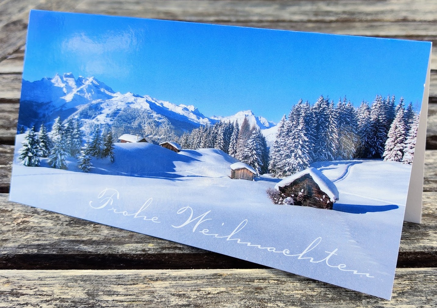 Weihnachtskarte aus hochwertigem 260g/m² Kunstdruckkarton mit Farbdruck. Schneebedeckte Gebirgslandschaft mit einigen Alm-Hütten ist abgebildet.